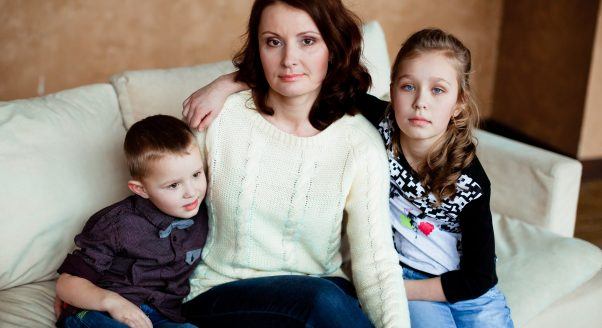 woman embraces son, daughter on couch