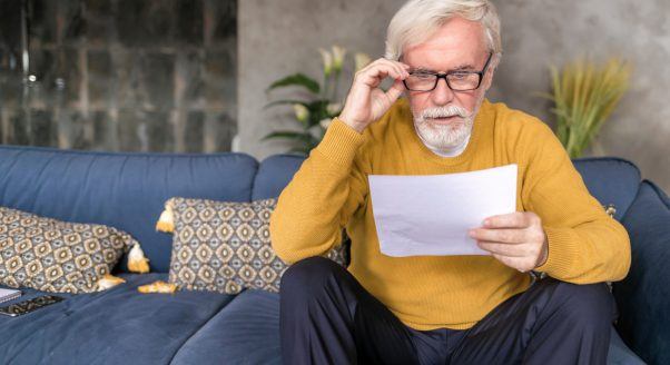 older man looks at financial papers concerned