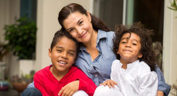 white grandmother smiles and hugs two biracial grandsons