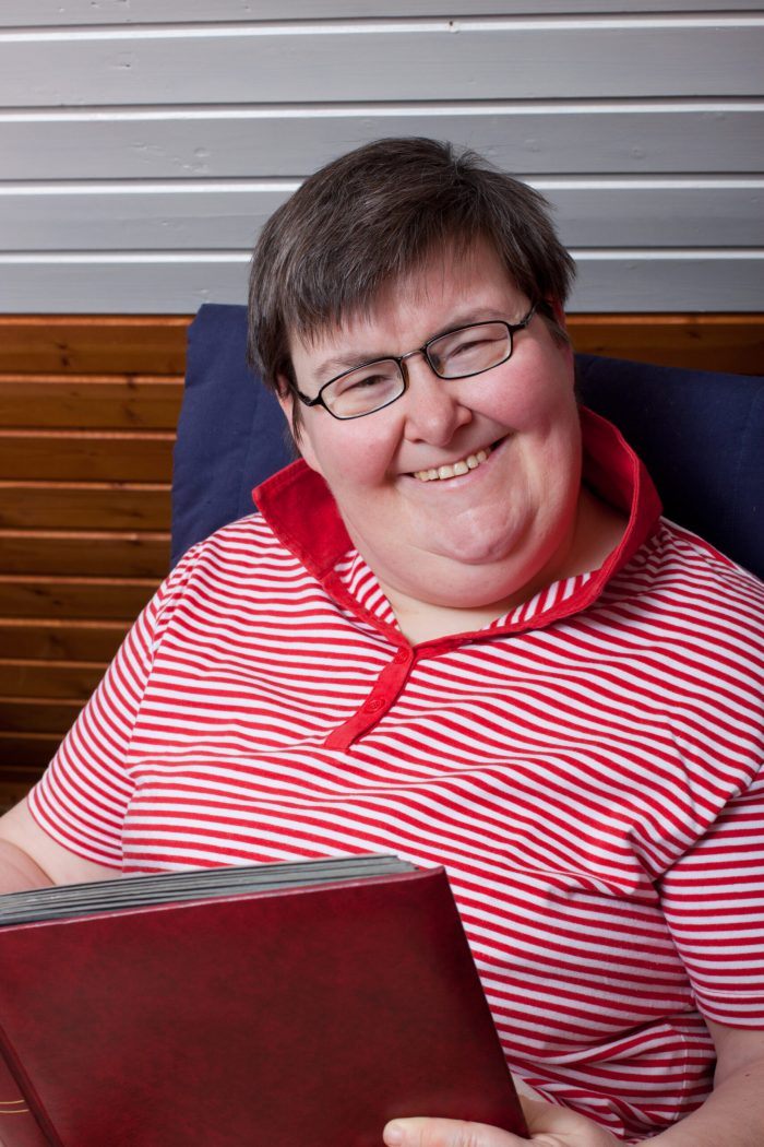 older woman with disability holds book and smiles