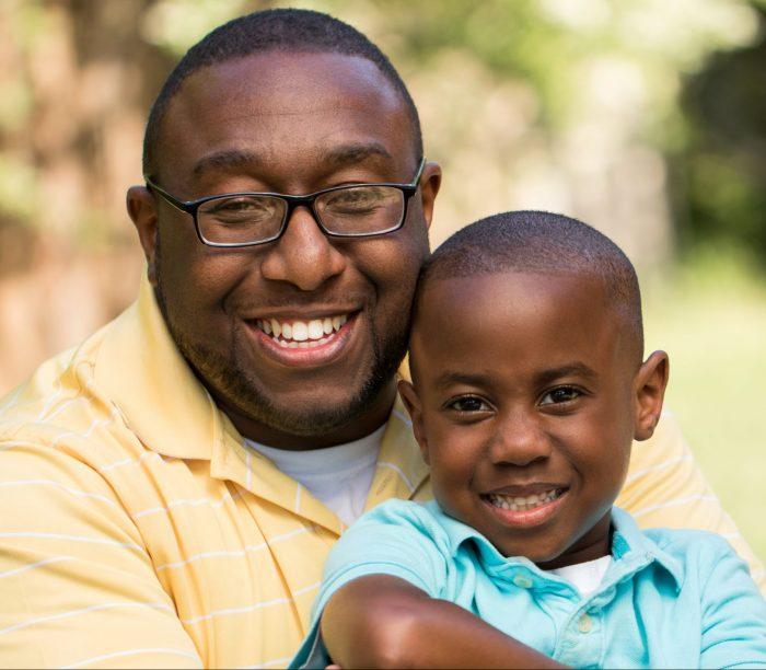 Black father hugging young son