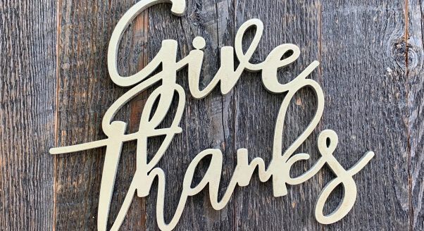 Give Thanks written in cursive on wood background