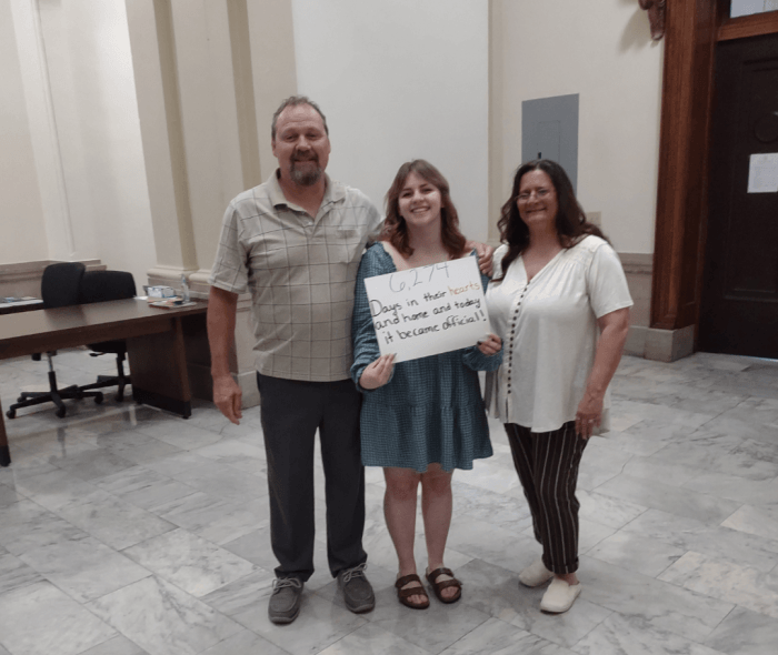 Richard, Gabby, and Dona on adoption day, smiling together at the courthouse.