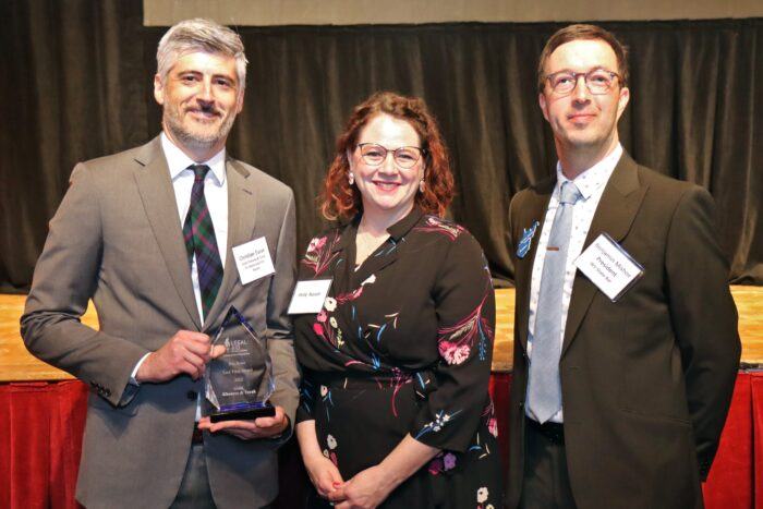 Christian Turak (on left) accepts the Pro Bono Law Firm Award from Molly Russell (center) and Benjamin Mishoe (right)