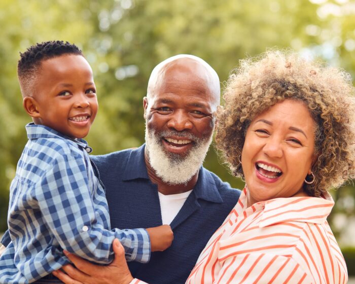 two grandparents hold their grandson and smile