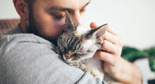man holds cat in hug