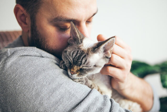 man holds cat in hug