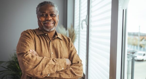 older man smiling standing next to window