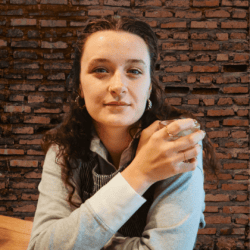 young woman looks ahead while sitting in coffee shop
