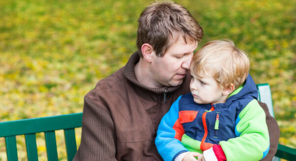 man sits on bench holding young son