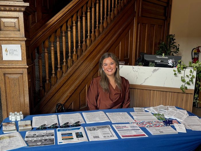 Kaylie sits at an outreach event table for Legal Aid of WV