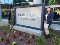 Volunteer Attorneys Angela and Jenna stand outside Jackson Kelly with the firm's sign.